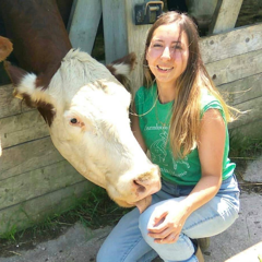 A photo of Edith Barabash at Farmhouse Garden Animal Home, kneeling down beside a cow.
